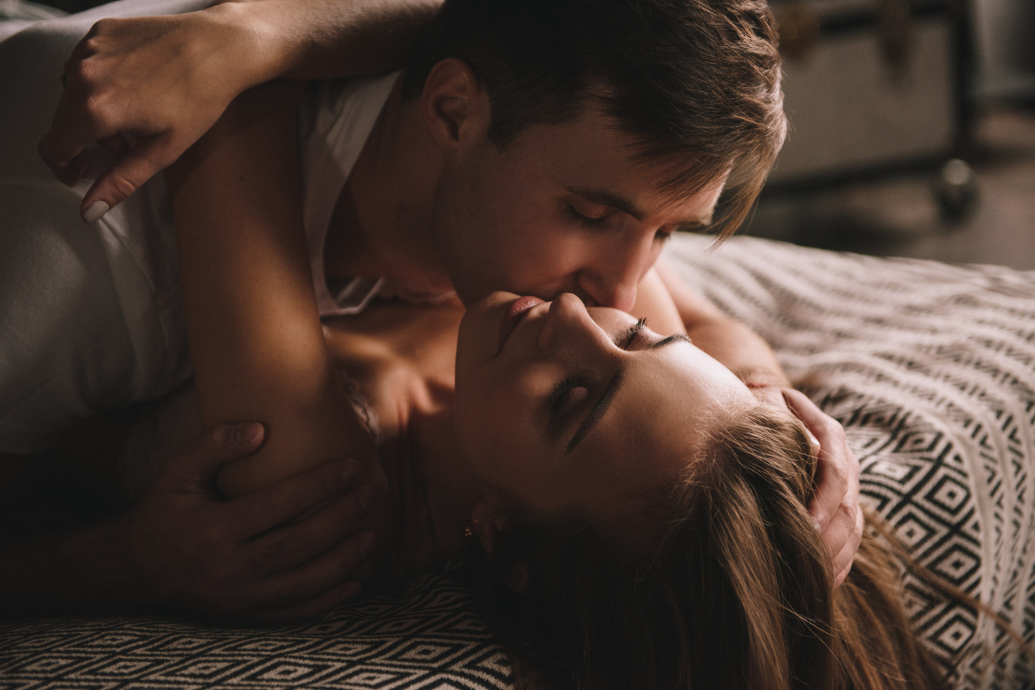 парень лежит сверху на девушке и целует ее в щеку